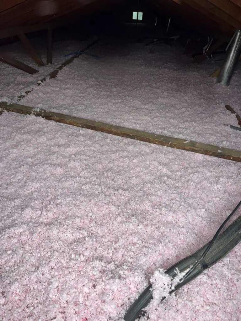 Attic insulation with pink fiberglass batts for energy efficiency and temperature control.