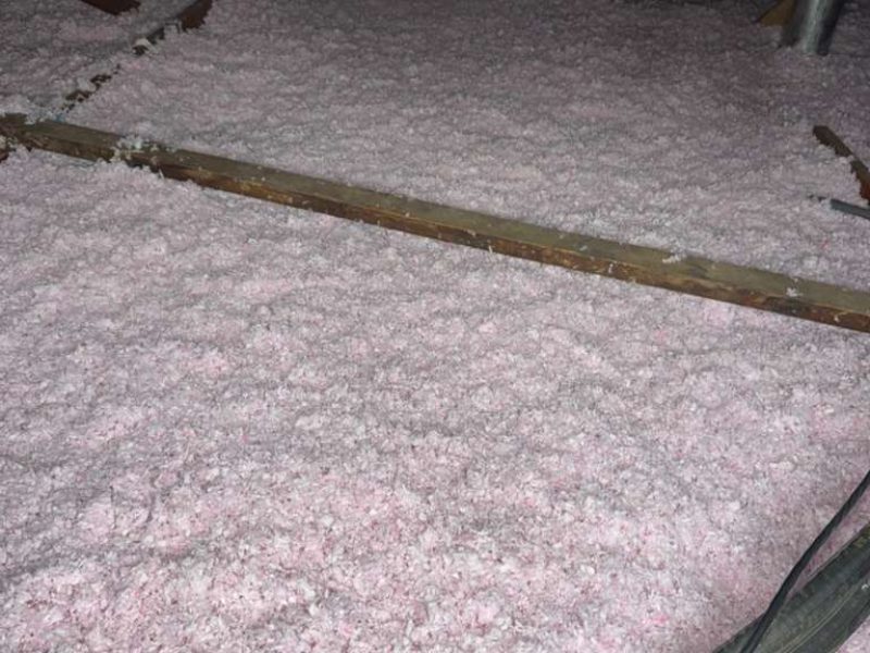 Attic insulation with pink fiberglass batts for energy efficiency and temperature control.